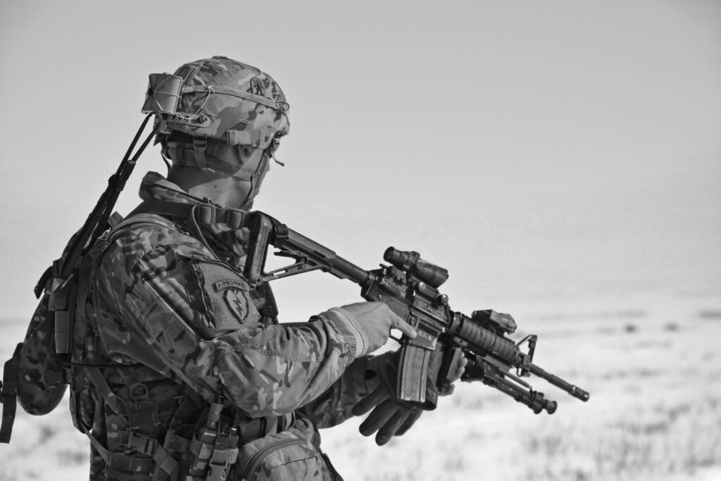 A soldier in military gear holding a rifle, captured in black and white.